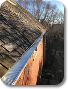 Mill finish gutter guard protection being installed on a wood shake roof home.